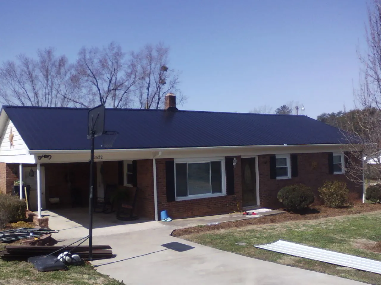 Finished dark blue metal roof on a brick ranch with a carport in Hummelstown