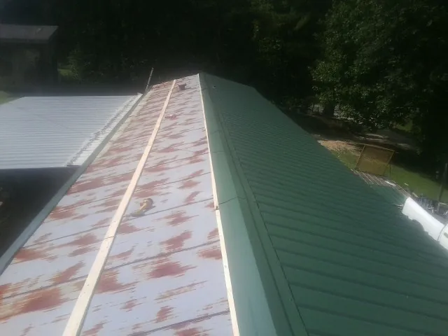 Old rusted panels beside newly installed green metal roofing — Wind Damage Roof Repair by Roofing Brothers in Hummelstown