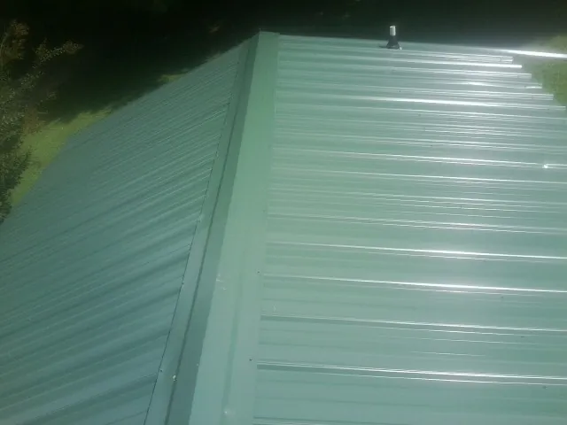 New green metal panels meeting at the ridge of a roof — Flat Roof Repair work by our crew in Hummelstown