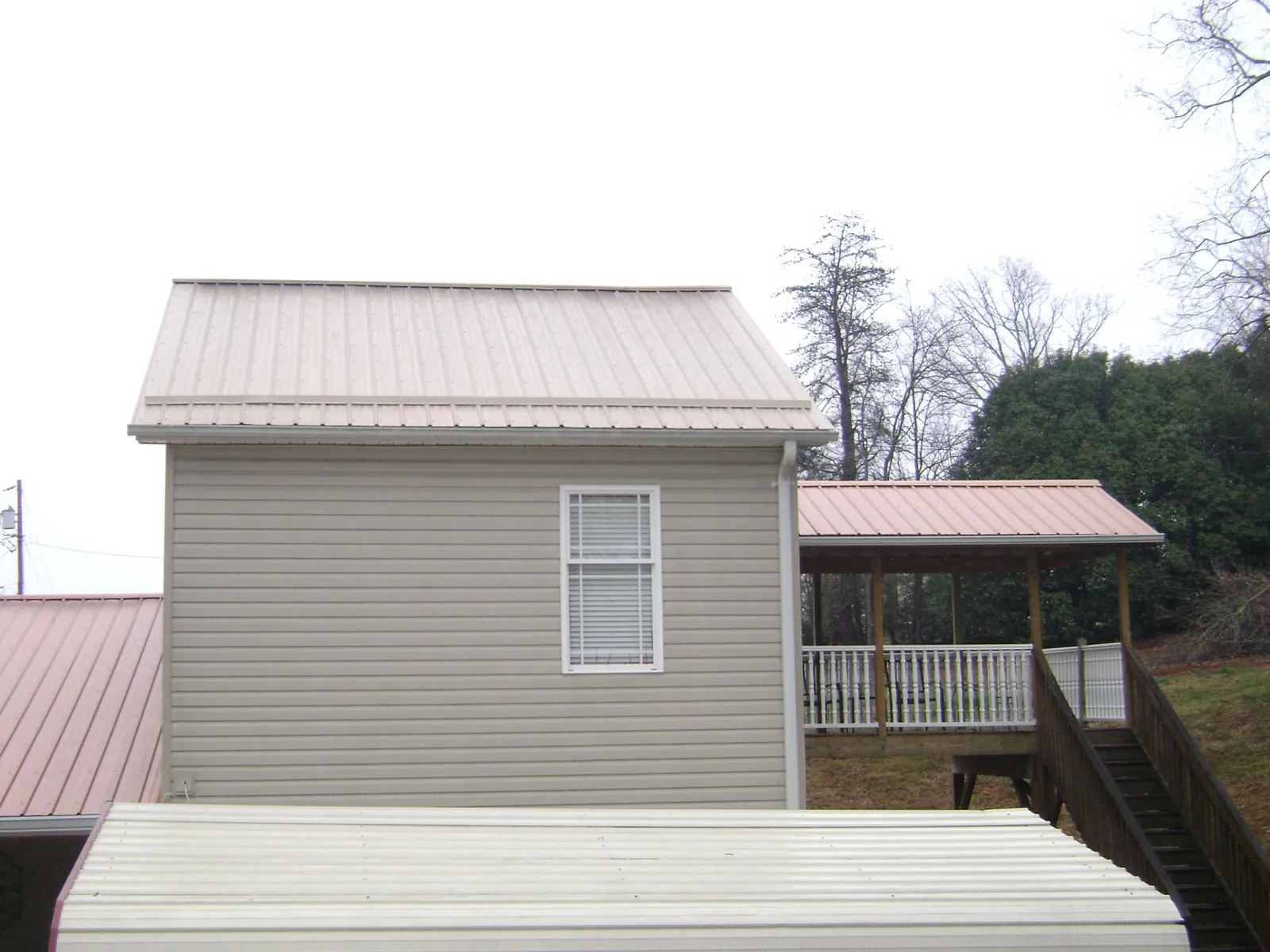 Tan metal roofs on a two story addition and attached porch, from a Roof Replacement job in Hummelstown