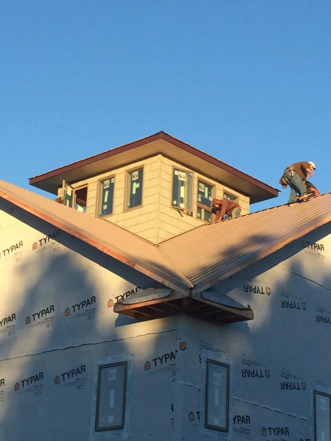 Roofers working around a rooftop cupola on a new metal roof at sunset — Roof Waterproofing in Hummelstown by Roofing Brothers